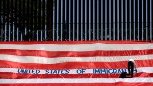 A man writes on a large U.S. flag as part of a protest called 'United States of Immigrants'