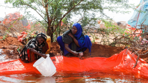 Two women collect water from a pan at the Kaxareey camp for the internally displaced people in Dollow, Gedo region of Somalia on May 24, 2022
