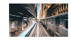 A Chicago elevated train car drives along the tracks through a station