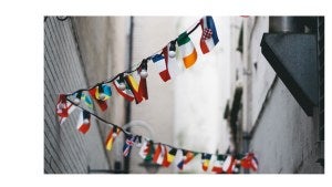 A string of various countries' flags hangs between two buildings