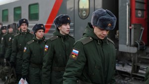 Russian conscripts called up for military service walk along a platform before boarding a train