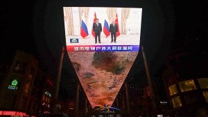 A giant screen broadcasts news footage of Chinese President Xi Jinping and Russian President Vladimir Putin