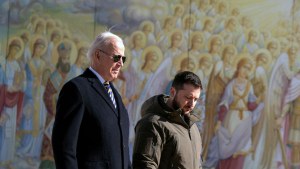 Biden and Zelenskyy walk to camera-right in front of a painting of saints. 