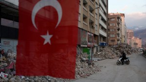 Turkish flag in front of rubble from earthquake.
