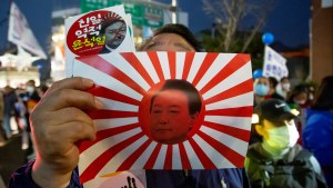 : Holding a mock rising sun flag of Japan disgraced with a portrait of South Korean President Yoon Suk-Yeol, a man attends protest marches in front of the Japanese Embassy in Korea