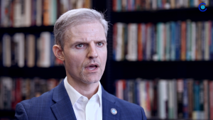 Paul Poast speaks in front of a bookshelf