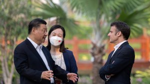 Macron and Xi speak outside with woman standing near Xi. 