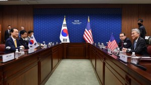 Tables with South Korea delegation on the left and US delegations on the right, flags in the center in front of a blue background.