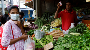 A woman purchases vegetables at an outdoor food market.