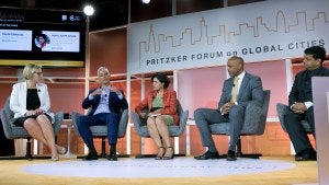 Five people sit in chairs on stage during an event