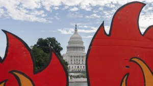 the U.S. Capitol is seen between cardboard cutouts of flames during a climate change protest