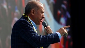 Erdogan pointing to the right holding a microphone