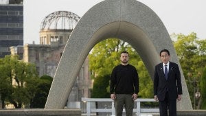Zelenskyy and Japan's leader near an arch outside.