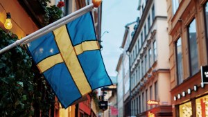 Swedish flag hangs on pedestrian street in evening.