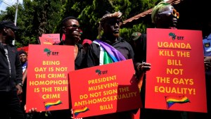 Activists hold red placards with yellow writing during their picket against Uganda's anti-homosexuality bill