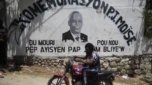 A moto-taxi driver rides past a mural featuring slain Haitian President Jovenel Moise.