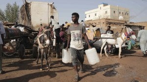 People gather to collect water in Khartoum, Sudan, Sunday, May 28, 2023.