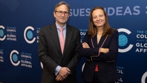 Sarah Gilbert and John Ettelson stand in front of the blue Council background with Council logos and "Issues, Ideas, Impact" behind them. 