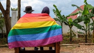A couple in Uganda wrapped in a gay pride flag, seen from behind.