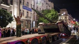 Members of the Wagner Group military company load their tank onto a truck on a street in Rostov-on-Don