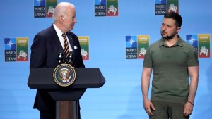 Biden stands at a podium on the NATO stage at left, Zelenskyy stands at right.