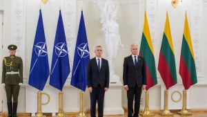 Lithuania's President Gitanas Nauseda and NATO Secretary General Jens Stoltenberg, left, pose in front of their respective flags, a soldier at left.