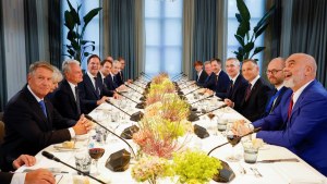 NATO leaders attend working dinner, viewed at the end of a table with white tablecloth and yellow centerpieces.