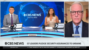 Screenshot of Anne Marie Green and Ramy Inocencio at a desk with blue background, live closeup of Ivo Daalder at right.