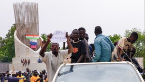 Supporters of mutinous soldiers in Niger hold a sign reading "down with Macron"