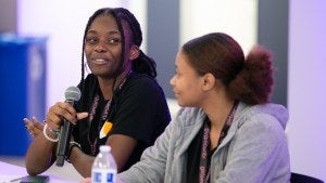 Young woman talking into a microphone.