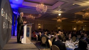 A person stands at a podium in front of an audience