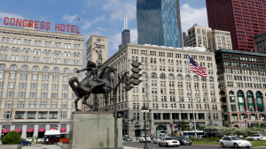 A statue of a man on horse with skyscrapers in the background
