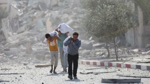 Palestinians walk by the buildings destroyed in the Israeli bombardment on al-Zahra, on the outskirts of Gaza City, Friday, Oct. 20, 2023.