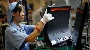 A person wearing gloves and a hairnet working in a factory line