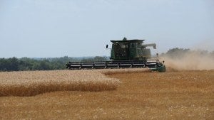 Farmer harvesting on a tractor in a field in Kansas. 