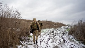 Two officers of Ukraine's state border guard walk to their positions in a snowy field in Sumy region, Ukraine, beneath a grey sky on Friday, Nov. 24, 2023.