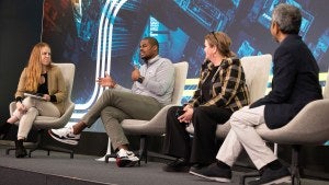 Four people sit in chairs on-stage during conversation