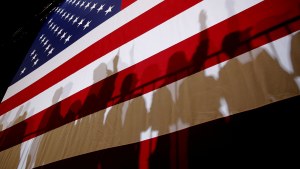Shadows of people standing in front of an American flag