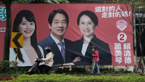 People pass by a campaign poster for Taiwan’s presidential election