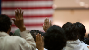 Migrants raise their hands to take the oath of citizenship