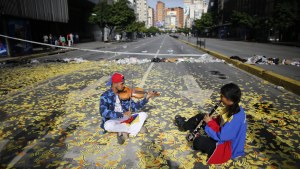 Musicians playing instruments on a road in Caracas littered with metro tickets