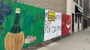 A wood fence painted with the Italian flag and a for sale sign