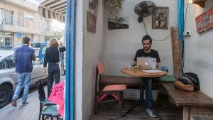 A man works from a cafe in the Florentin neighborhood of Tel Aviv, Israel.