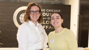 Two people stand in front of the Chicago Council logo