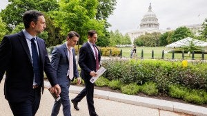 Three people walk in front of the U.S. Capitol Building