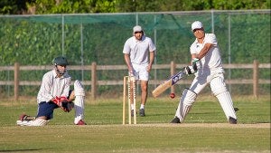 Three athletes competing during a cricket match