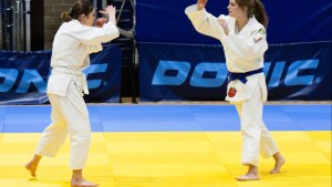 Two people on a yellow mat during a judo match