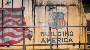 A Union Pacific Railroad locomotive with a logo that reads "BUILDING AMERICA" and an American flag on its side.