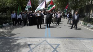 Protesters carry Iranian and Palestinian flags, while an image of the Israeli flag is painted on the ground