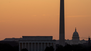 A sunrise casts the Lincoln Memorial, Washington Monument, and US Capital in orange on June 21, 2024.